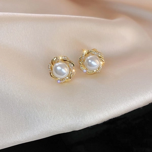 Macro shot of pearl stud earrings with gold twisted borders and sparkling crystals