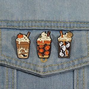 Three Halloween enamel pins with pumpkin and ghost motifs on a blue denim jacket pocket