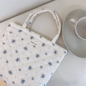Close-up of quilted floral tote bag with blue patterns and a simple wish label