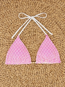 Detail of pink lace bikini top with pearl chain and golden ring on a beach mat