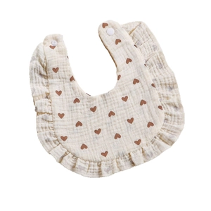 Muslin cotton baby bib with ruffles and heart print featuring adjustable snap buttons