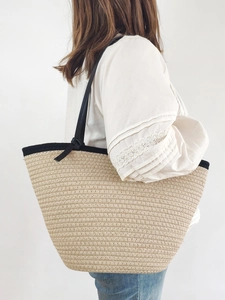 Minimalist beige woven cotton tote bag with black handles for beach and vacation use