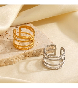 Detail of layered gold and silver stainless steel rings on stone and silk fabric