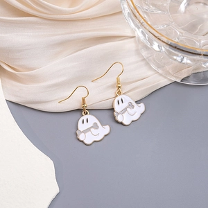 Detailed view of white and gold ghost earrings on a silk background with glassware