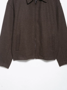 Détail d'une veste en laine marron foncé avec fermeture éclair et texture de laine