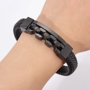 Close-up of men's black braided leather bracelet with hollow metal clasp on wrist