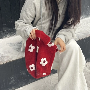 Macro shot of red plush faux fur tote bag with white flower embroidery in snow