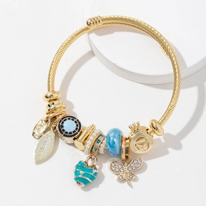 Golden beaded bracelet featuring butterfly, blue heart, and crown charms on white background