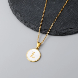 Detail of 18K gold necklace with a round white shell pendant and letter L engraving
