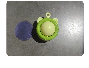 Detail view of rotating catnip toy with green base, yellow ball, and purple dust cover