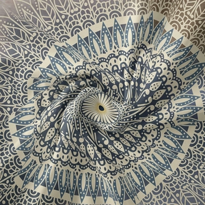 Detail of bohemian mandala tapestry featuring intricate geometric floral patterns in blue and beige
