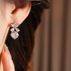 Gros plan de boucles d'oreilles fleurs ajourées serties de zircons portées par un mannequin