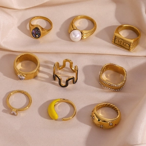 Close-up of assorted 18K gold plated rings with pearls and zircon on beige silk fabric