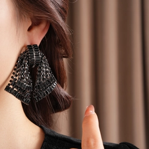 Close-up of oversized black bow earrings with sparkling rhinestones worn by a model