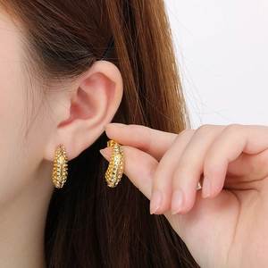 Détail macro de boucles d'oreilles en C plaquées or 18K avec zircons blancs pavés