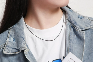 Close-up of minimalist black snake bone necklace on model wearing white shirt