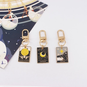 Three gold alloy tarot card keychains featuring Wheel of Fortune, Moon, and Star designs