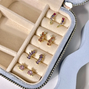 Macro detail of colorful zircon stud earrings set in a blue velvet travel jewelry case