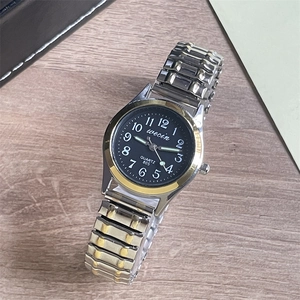 Detail of quartz watch with luminous gold and silver stainless steel stretch band