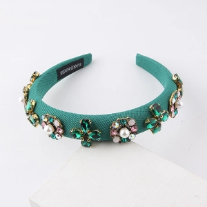 Close-up of handmade green knit headband featuring pearls, rhinestones and a woven label
