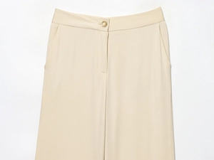 Détail du pantalon beige à taille haute montrant un bouton doré et un tissu sergé