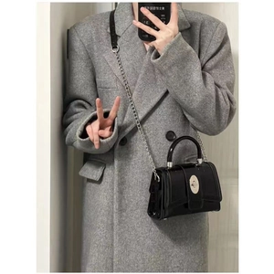 Glossy patent leather crossbody bag with silver chain strap shown in lifestyle mirror selfie