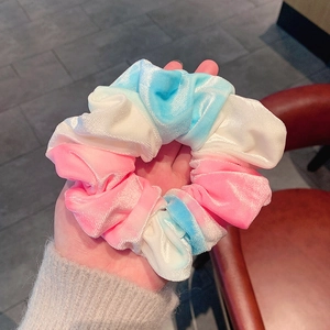 Close-up of a large velvet scrunchie featuring a pink, blue, and white gradient design