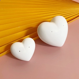 Minimalist white heart-shaped ceramic earring display stand set on pink background