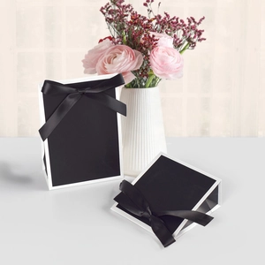 Close-up of elegant black gift bags with white piping and smooth satin bow decorations