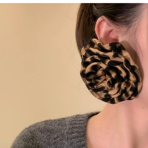 Close-up of a large leopard print fabric rose earring on a model for a vintage look