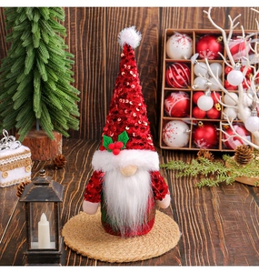 Détail d'un gnome de Noël à paillettes rouges avec barbe en peluche sur table festive en bois