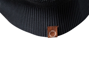 Close-up of black ribbed knit texture with a brown leather logo patch on a men sweater
