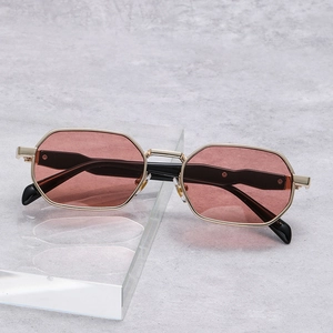 Detalle de gafas de sol octogonales de metal dorado con lentes marrón rojizo sobre gris
