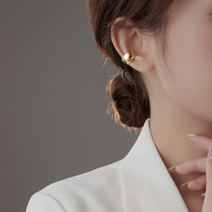 Detailed view of a wide polished gold ear cuff on a model showing minimalist style
