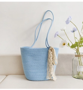 Detail of light blue cotton rope woven tote bag featuring a decorative lace ribbon accessory