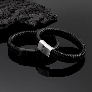 Macro detail of braided leather bracelets with brushed steel magnetic clasps on reflective surface