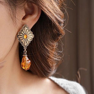 Detail of vintage bronze drop earrings with diamond texture and amber gemstone on model