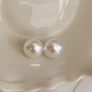 Detailed view of 16mm glossy white pearl earrings displayed in a minimalist ceramic bowl