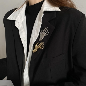 Detailed view of stylish gold and silver hand brooches on a black suit lapel