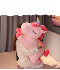 Close-up of soft pink unicorn plush with rainbow horn and wings held by model