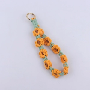 Detail of handmade woven sunflower keychain with cotton rope and golden metal ring