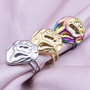 Three minimalist stainless steel rings with abstract faces on pink silk fabric