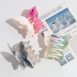 Detailed close-up of butterfly hair clips in acetate marble and ink wash patterns