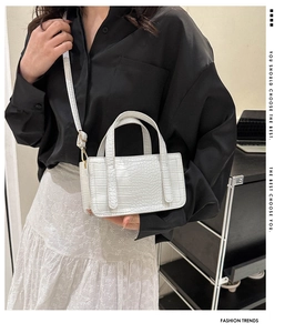 Detail of white crocodile pattern crossbody bag with golden hardware and long strap