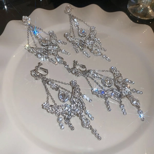 Detailed macro view of silver water drop tassel earrings with glittering crystals on a tray