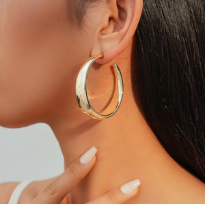 Classic golden C-shaped hoop earrings featuring a smooth metallic finish on model