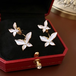 Macro détaillée de boucles d'oreilles papillon dorées avec incrustation blanc nacré