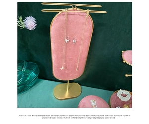 Detailed view of pink velvet jewelry display stand with golden metal necklace holder