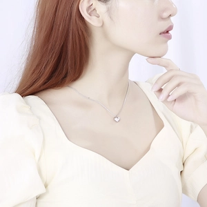 Gros plan d'un collier avec pendentif coeur argenté porté sur la clavicule du mannequin