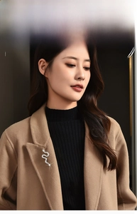 Detailed view of a silver snake brooch with inlaid zircons on a camel wool coat